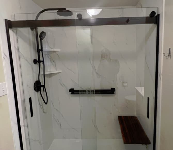 accessible shower is walk in with a shower seat, handrail, shelves, and adjustable shower
