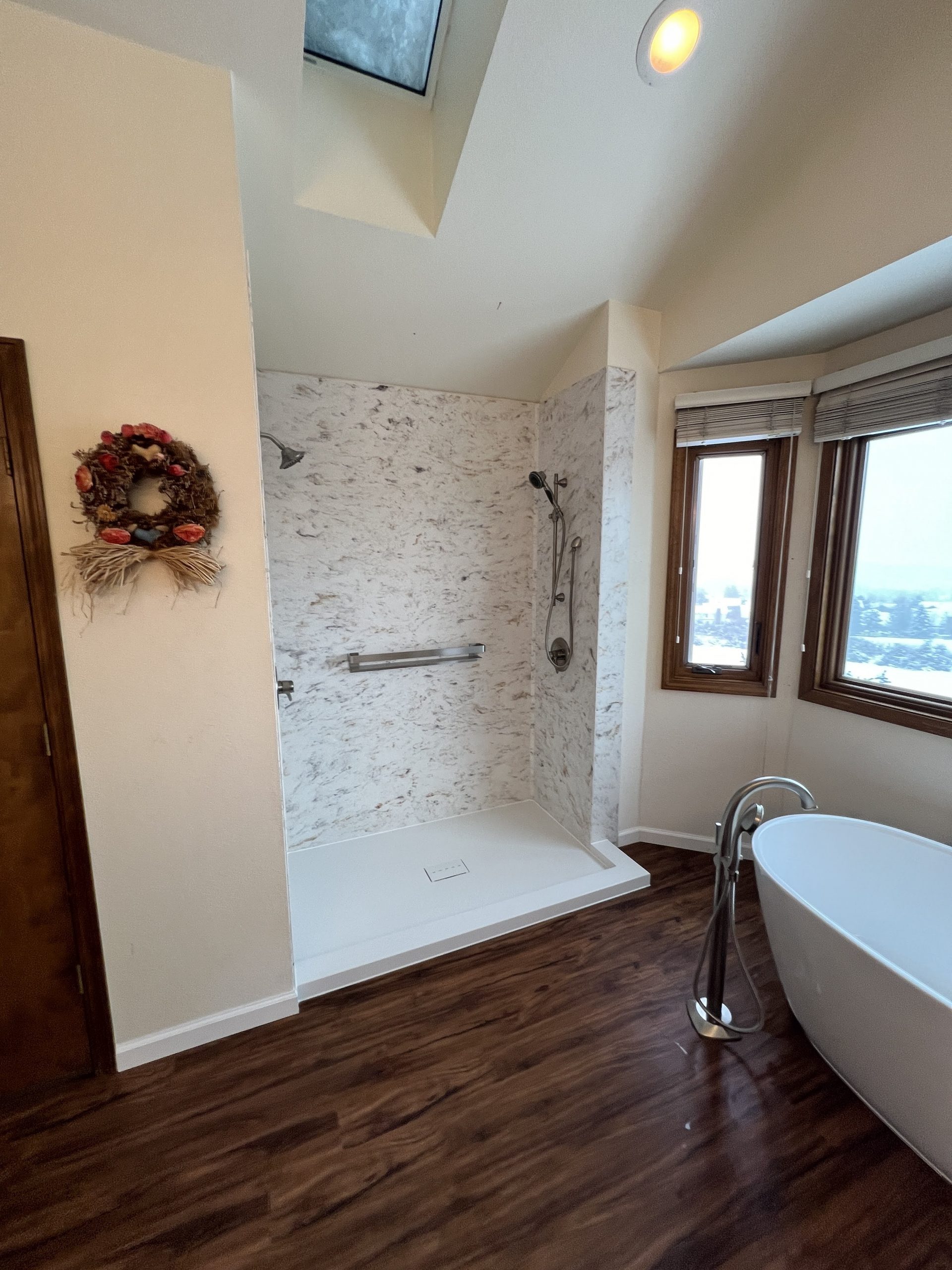 bathroom with a walk in shower and stand alone bathtub and wood floors with big windows
