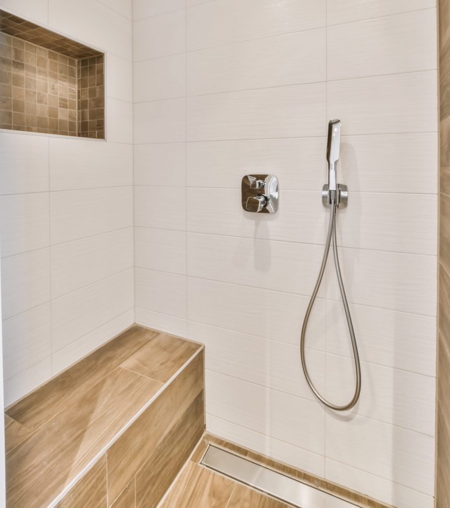 handicap bathroom that has a walk in shower with a bench and hand held shower head
