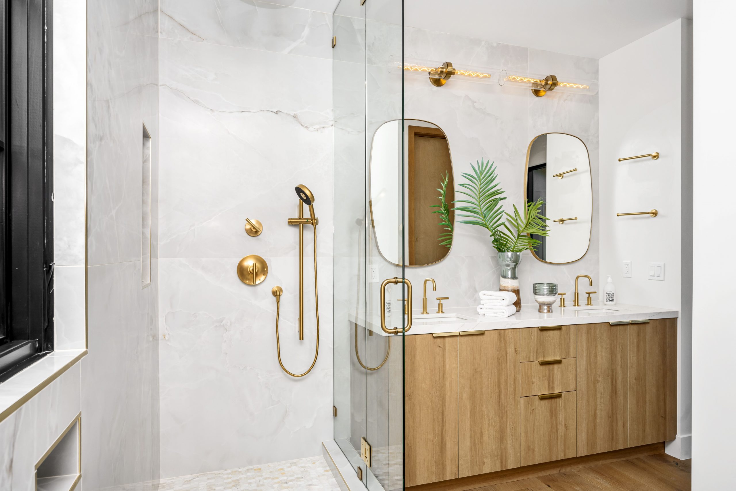 modern shower renovation with walk in shower that has glass doors and gold fixtures